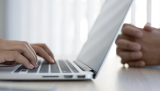 A close up of a person's hands typing on a computer
