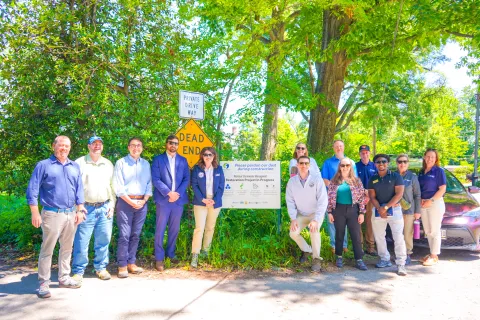 Elfreth, Kurtz, etc. stand at sign outside of first watershed project